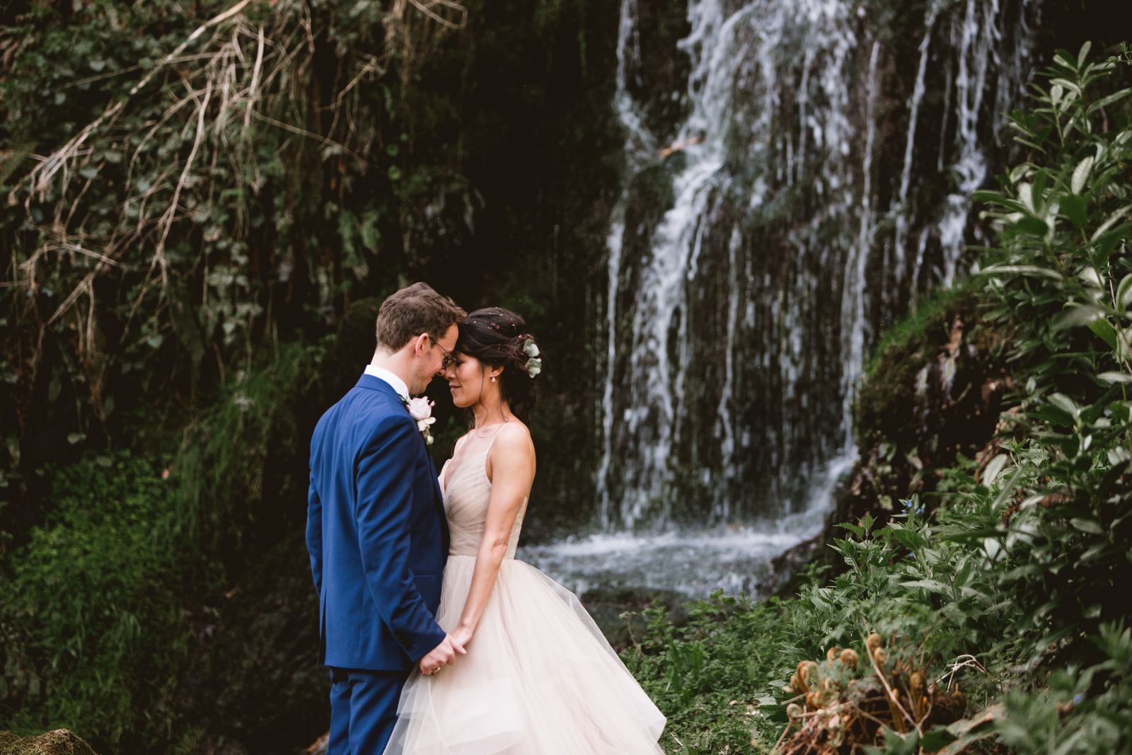 Bride and groom pose together beside the waterfall at Hestercombe Gardens